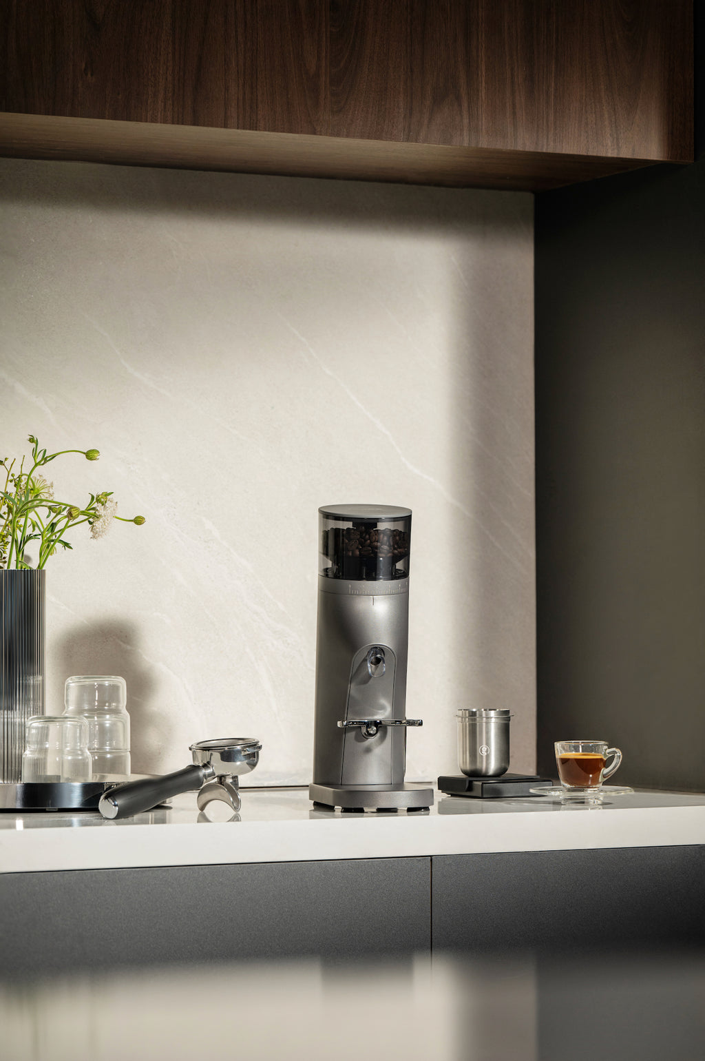 Gemilai G9010C Coffee grinder on a kitchen counter with a cup of coffee and a plant in the background.